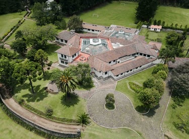 Fotografía con dron de mansión colonial de paredes blancas con techo naranja, cúpulas rodeada de naturaleza Quito Ecuador