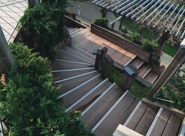 Winding wooden outdoor staircase with metal non-slip stair treads and green landscaping.