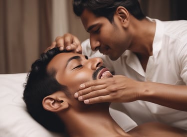 A woman is lying on a blue towel with her eyes closed, receiving a back massage. The hands of the person giving the massage are visible, applying gentle pressure to the woman's upper back.