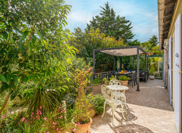 La terrasse ombragée au sud, avec espace repas et coin détente, vue sur le jardin paysager