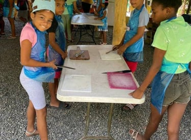a group of children are standing around a table for crafts