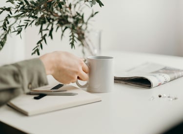 Hand bij koffie en notitieblok, mini-moment van zelfreflectie.