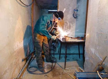student wearing welding glasses and welding a metal object in a welding room