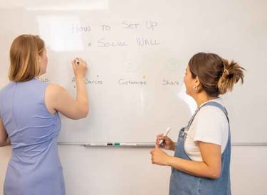 2 women writing on a white board 
