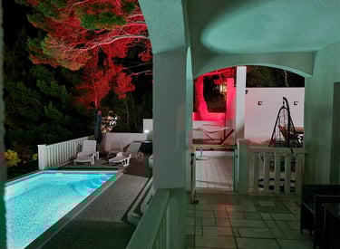 The photograph shows a part of the ground-floor balcony, pool and a courtyard with ambient lighting.