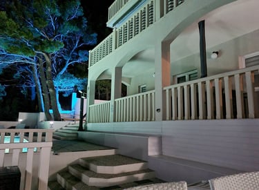 The photograph depicts the ground level of the house and a part of the yard with ambient light. 