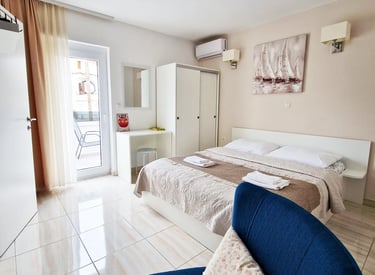 room with bed, chairs, closet, desk and window with balcony