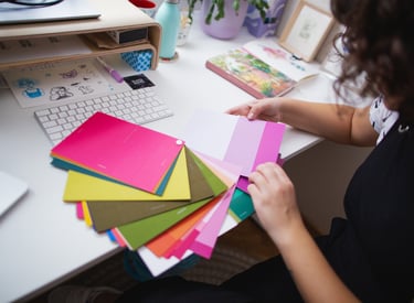 Materiales de trabajo de Blanca, incluyendo una libreta de bocetos, lápices de colores y muestras de diseño.