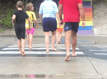 A barefoot Australian family crossing a pedestrian crossing