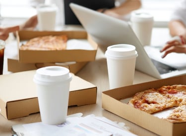 A table with pizza boxes and takeout cups, during a corporate working activity .