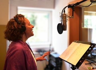 eine Frau singt in ein Mikrofon in einem Tonstudio