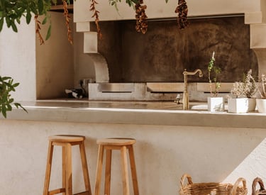 Zona exterior de un bar con taburetes de madera, grill y barbacoa