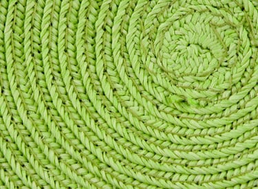 Textura de primer plano de un mantel individual tejido de color verde lima con un patrón en espiral.