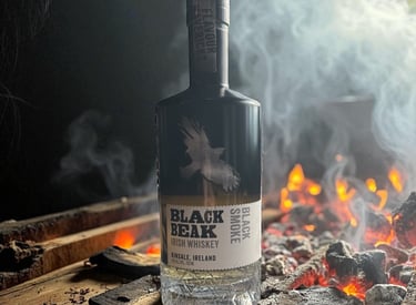 Black Beak Black Smoke Irish Whiskey bottle standing near burning charcoal embers and smoke.