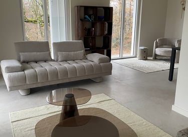 Salon moderne avec un canapé beige capitonné à rainures, des tables basses en verre