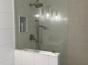 Modern walk-in shower featuring gold fixtures, vertical subway tile, and a glass partition wall.