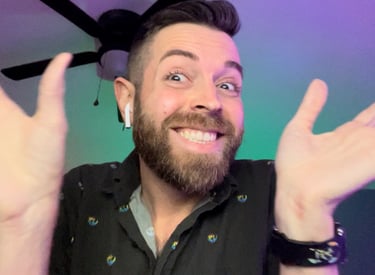 A smiling man with a beard waving his hands excitedly during a video call with colorful lighting.