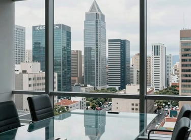 A high-angle view of a modern business district in a major South American city through a window of a sophisticated legal office. A glass meeting table reflects the light gray and medium blue colors of the professional environment.