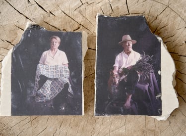 Antique style portraits of an elderly couple printed on broken ceramic slabs over a wood stump.