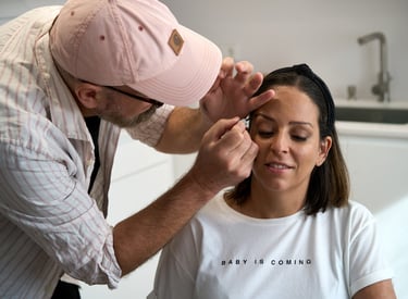 Professional makeup artist applying eye makeup to a woman in a white t-shirt during a beauty session.