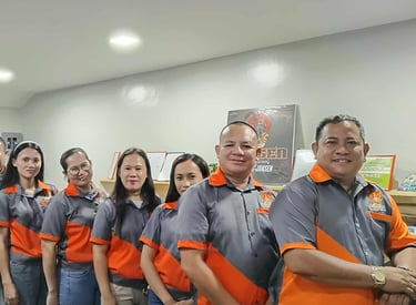 A team of professional employees posing together in matching orange and grey company uniforms.