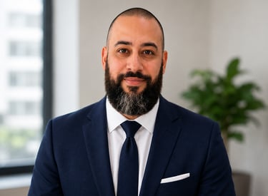 Professional headshot of a bearded man in a navy blue suit and tie for business profile.