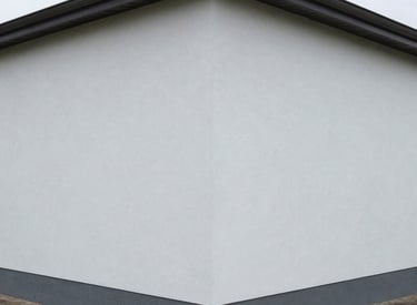 Close-up of professional painter applying smooth exterior wall paint.