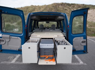 1st prototype WOODSYBOX with pull-out kitchen drawers, portable fridge, and sink unit in a blue van.
