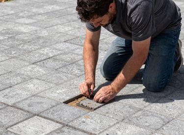 A landscape professional installs decorative stone pavers on a patio walkway.