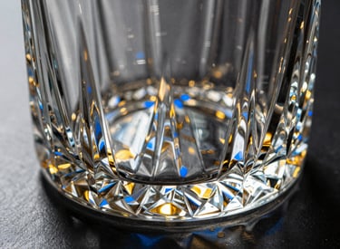 Macro detail shot of a heavy crystal decanter base with geometric cuts refracting golden light, azure blue shadows, 35mm