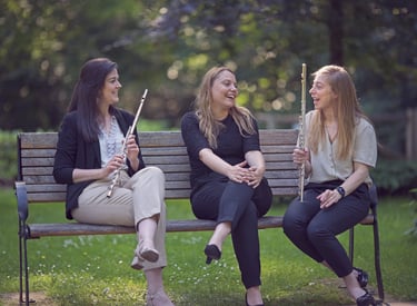 three women sitting on a bench in a park