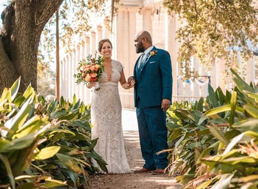 a bride and groom walking down a path in front of a building