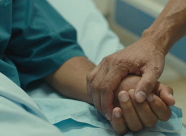 Close-up photography of a South American / Brazilian volunteer's hand gently holding a patient's hand on a hospital bed, soft lighting, warm and compassionate atmosphere, using dark teal and seafoam green tones.