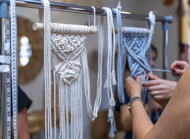 Tejidos de macramé colgando de soportes de madera, los cuales están sujetos a una estructura metálica.