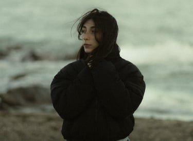 a woman in a black jacket standing on a beach