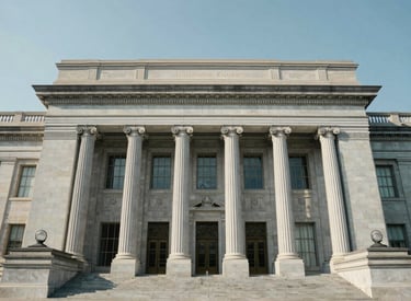 A wide-angle, professional architectural shot of a North American federal government building facade in Washington D.C. under a clear sky. The lighting is bright and clean, emphasizing the light gray stone pillars and the serious, accessible nature of the institution.