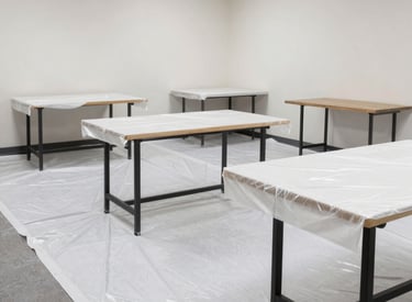 Commercial office space being painted white with professional tools and protective sheets on the floor.