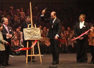 Prince Edward cutting a red ribbon with scissors during an official plaque unveiling in Shrewsbury 