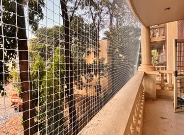 A freshly installed safety net securing a high-rise balcony overlooking Mumbai's skyline.