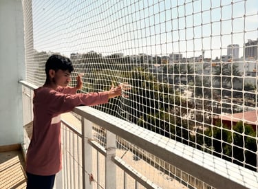 Close-up of a technician inspecting and repairing a pigeon net on a balcony.