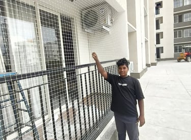 Technician carefully installing a pigeon net on a high-rise balcony in Mumbai.