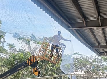 Technician carefully installing pigeon nets on a high-rise balcony.