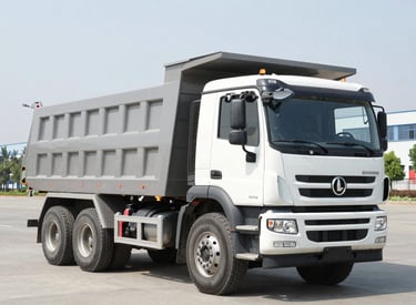A powerful dumper truck loaded with earth on a construction site at sunset.
