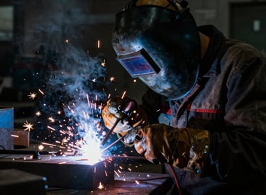 Sander welding metal parts in a bright workshop with tools around.