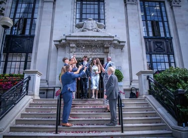 Newlywed couple exits Islington town hall while guests throw white confetti on the stone steps.