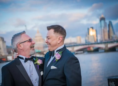 two grooms smiling at each other on london Southbank