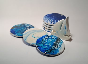 Handmade blue and white resin ocean coasters with cells and a small sailboat figurine.