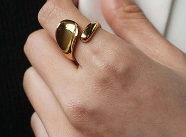 Mujer elegante que luce un anillo de oro grueso con un diseño escultural orgánico y moderno.