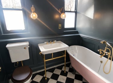 Luxury bathroom with a pink clawfoot tub, gold fixtures, and black and white checkered floor tiles.