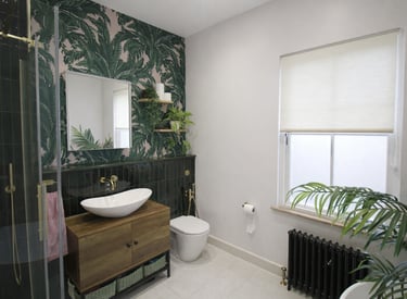 Modern bathroom featuring tropical palm leaf wallpaper, a wooden vanity, and gold fixtures.
